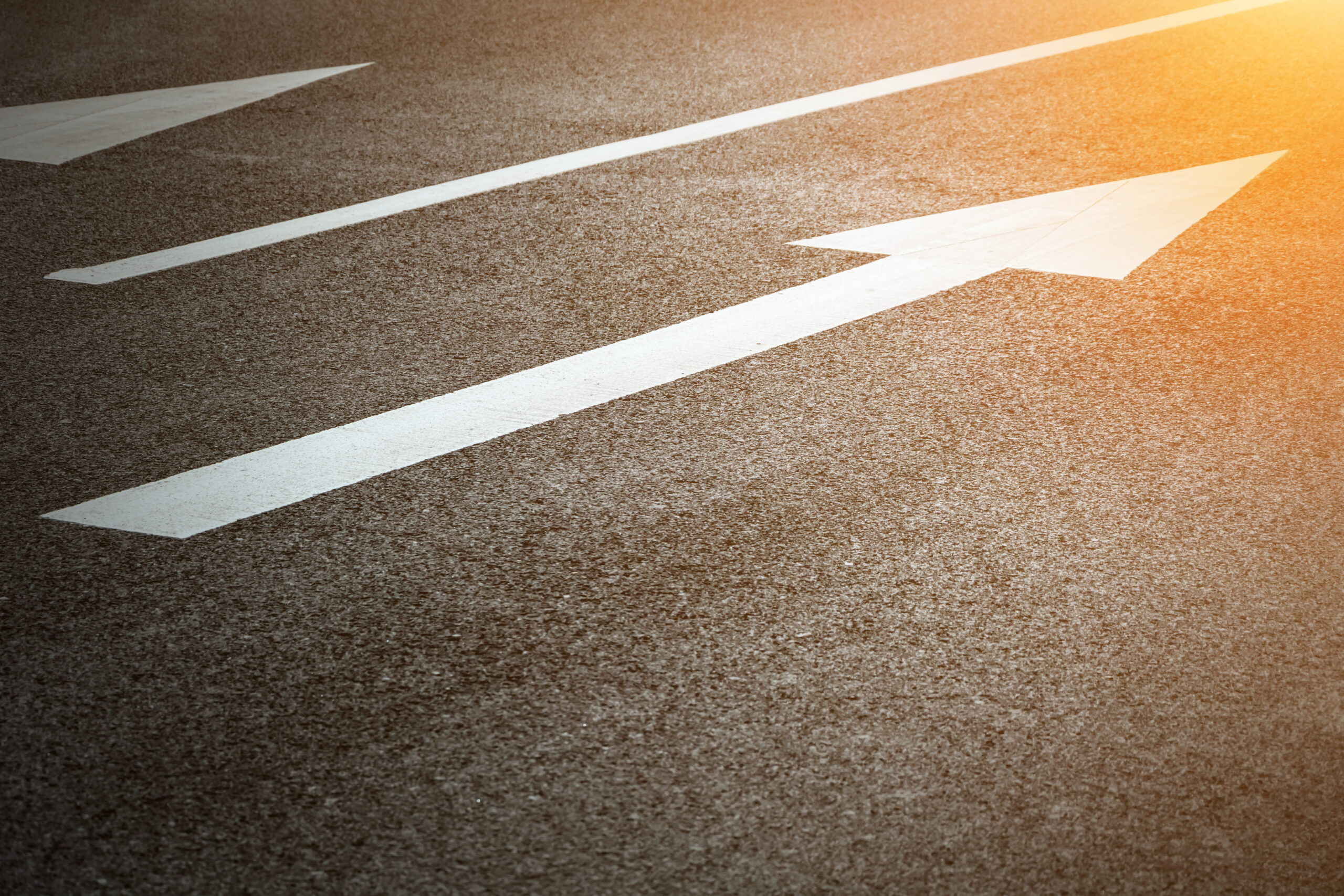 Directional arrow on a sunlight road Directional arrow on a sunlight road